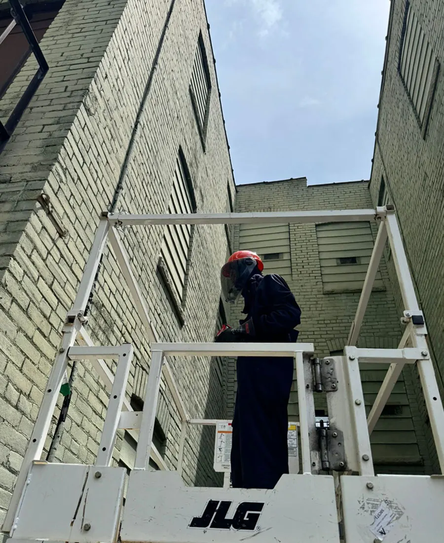 LAX technician working from a lift between brick buildings